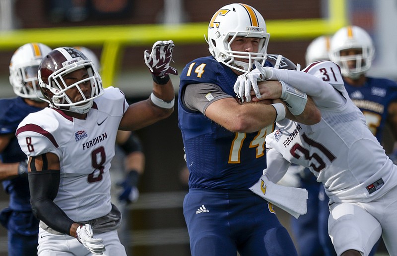 UTC quarterback Jacob Huesman (14) protects the ball as he's hit on a long run by Fordham defensive backs Caleb Ham, right, and Lourenzo Smith in the first half of the Mocs' FCS playoff football game against Fordham at Finley Stadium on Saturday, Nov. 28, 2015, in Chattanooga, Tenn.