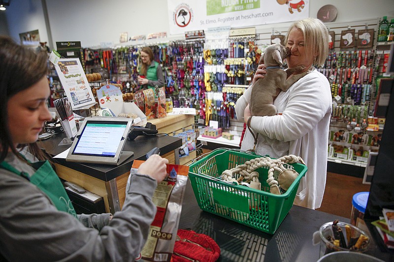 Lacey Varnon's dog, Harvey, licks her face as clerk Aleise Cline checks her out at Nooga Paws on the Small Business Saturday shopping day Saturday, Nov. 28, 2015, in Chattanooga, Tenn. The annual day encourages shoppers to shop locally.