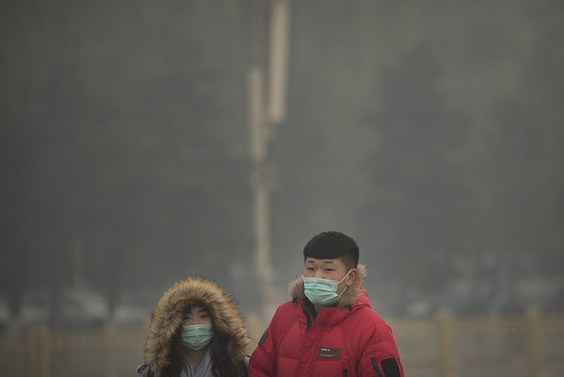 
              People wearing face masks walk across Tiananmen Square on a day with poor air quality in Beijing, Saturday, Nov. 28, 2015. Air pollution in Beijing reached hazardous levels on Saturday as smog engulfed large parts of the country despite efforts to clean up the foul air. (AP Photo/Mark Schiefelbein)
            