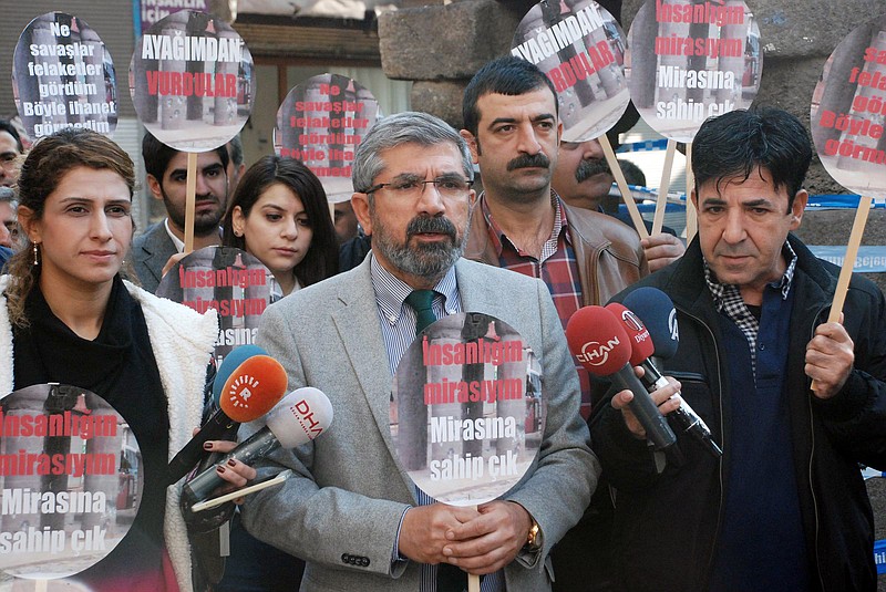 
              Tahir Elci, the head of Diyarbakir Bar Association, speaks to the media shortly before being killed in Diyarbakir, Turkey, Saturday, Nov. 28, 2015. Elci, a prominent lawyer, who faced a prison term on charges of supporting Turkey's Kurdish rebels, has been killed in an attack in Diyarbakir. Elci was shot on Saturday while he was making a press statement in front of a historical mosques damaged during fightings between Kurdish rebels and security forces. Elci holds a placard that reads: " Let's protect humanity heritage." (IHA agency via AP) TURKEY OUT
            