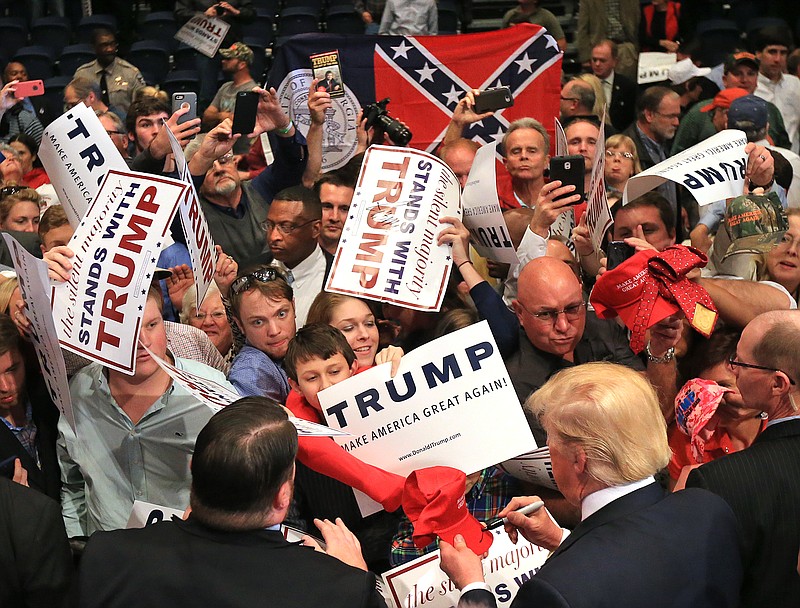 
              Republican presidential candidate Donald Trump works the crowd at the conclusion of his second campaign visit to Georgia at the Macon Centreplex Coliseum while a member of the crowd holds up the former flag of the state on Monday, Nov. 30, 2015, in Macon, Ga.  (Curtis Compton/Atlanta Journal-Constitution via AP)
            