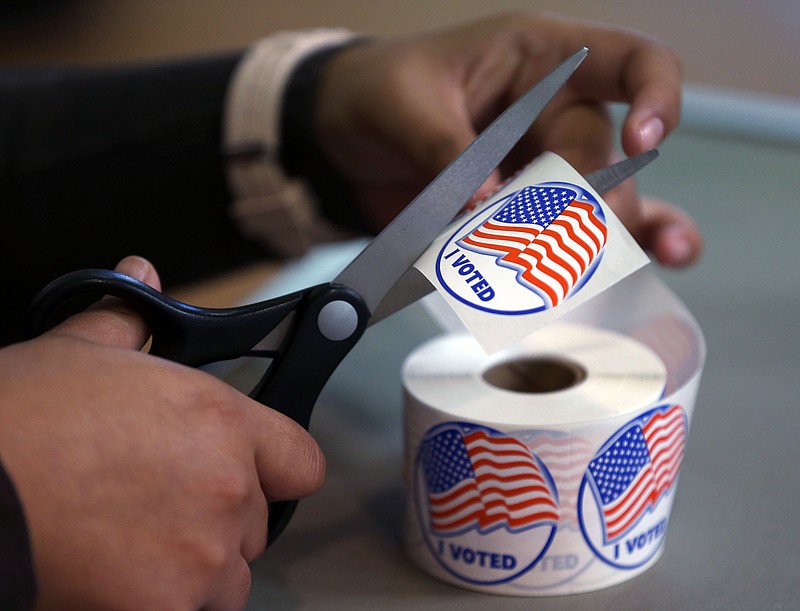 A volunteer hands out stickers to voters in Carson City, Nev., on Tuesday, Nov. 4, 2014. Nevada voters may be going to the polls in record low numbers. The Secretary of State reported that as of 3:30 p.m., almost 430,000 ballots had been cast in Tuesday's election. (AP Photo/Cathleen Allison)