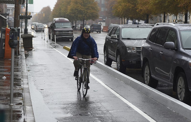 Judy Scoggins, an art student at UTC, uses one of the bike lanes on Broad Street on Monday, Nov. 30, 2015, in Chattanooga, Tenn. After a grace period, the Chattanooga Parking Authority will begin ticketing businesses and vehicles that violate the new downtown bike lane policy. 