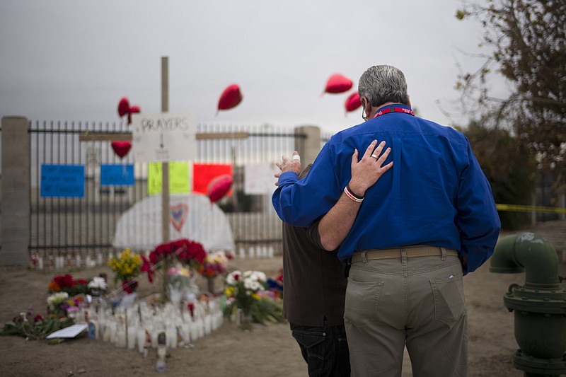 
              Chaplain Chuck Bender, right, prays with Michael Davila at a makeshift memorial honoring the victims of Wednesday's shooting rampage, Friday, Dec. 4, 2015, in San Bernardino, Calif. The FBI said Friday it is officially investigating the mass shooting in California as an act of terrorism, while a U.S. law enforcement official said the woman who carried out the attack with her husband had pledged allegiance to the Islamic State group and its leader on Facebook. (AP Photo/Jae C. Hong)
            