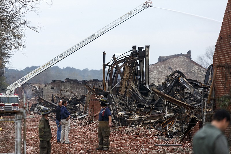 Water is sprayed on the burned wreckage of the Barwick Mills building Tuesday, Nov. 17, 2015, three days after a fire destroyed much of the building in Lafayette, Ga. The EPA has been taking air samples to assess the impact of the fire.