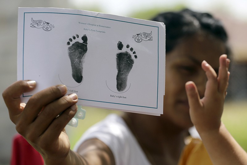 
              In this Sept. 16, 2015, photo, a woman in Sullivan City, Texas, who said she entered the country illegally shows the footprints of her daughter, reaching into photo, who was born in the United States, but was denied a birth certificate. Texas has for seven years said it won’t accept Mexican identification cards when issuing birth certificates for children of people in the United States illegally. But it doesn’t appear to have stepped up enforcement until recently, amid mounting political pressure to get tougher on immigration, documents obtained by The Associated Press show. (AP Photo/Eric Gay)
            