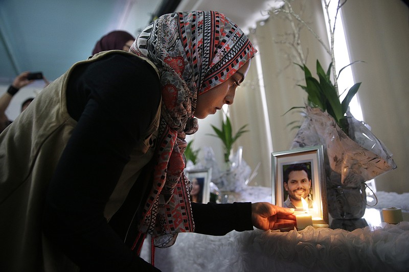 Khadija Zadeh lights candles set up next to the framed photos of 14 victims killed in in Wednesday's shooting rampage before the start of the memorial service at the Islamic Community Center of Redlands, Sunday, Dec. 6, 2015, in Loma Linda, Calif. The FBI said it is investigating the rampage as a terrorist attack. (AP Photo/Jae C. Hong)