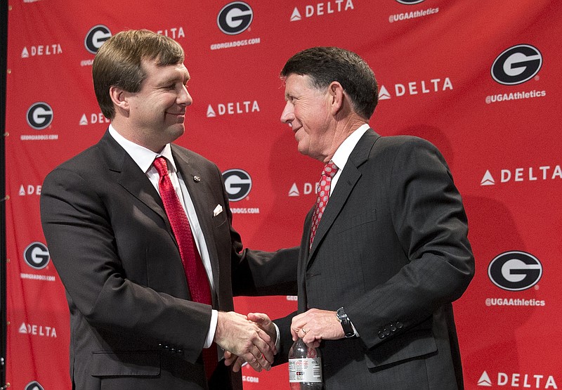 Alabama defensive coordinator Kirby Smart, left, speaks to Georgia athletic director Greg Mcgarity after during a press conference where he was introduced as Georgia's new head football coach  Monday, Dec. 7, 2015, in Athens, Ga. Smart will stay with the Crimson Tide through the NCAA college playoffs. (AP Photo/John Bazemore) 