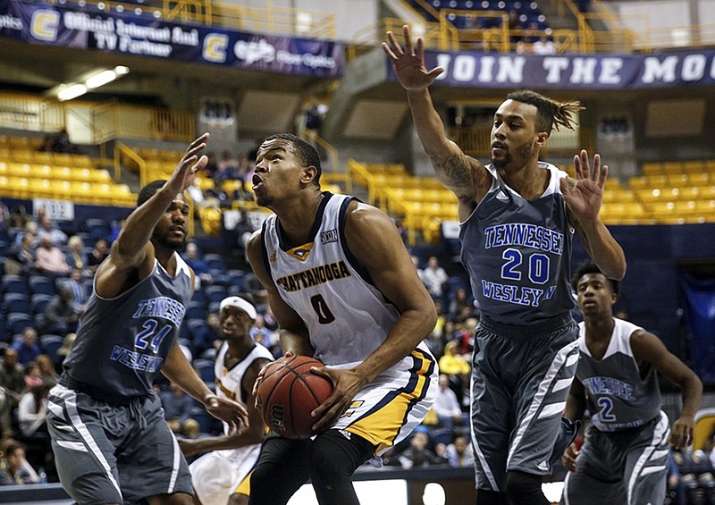 UTC junior forward Chuck Ester drives between Tennessee Wesleyan guards Matt Brown, right, and Leland Robinson during the Mocs' home game Tuesday.