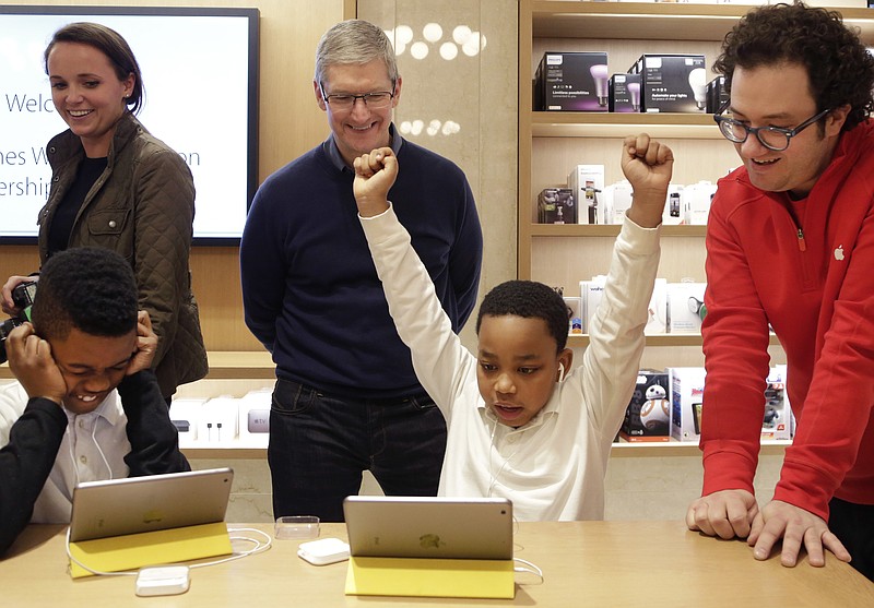 
              Jaysean Erby raises his hands as he solves a coding problem as Apple CEO Tim Cook watches from behind at an Apple Store, Wednesday, Dec. 9, 2015 in New York. Third graders from PS 57 James Weldon Johnson School were invited to the store to play a Star Wars game hosted on code.org. Apple is hosting Hour of Code events around the world as part of Computer Science Education Week which runs through Sunday. (AP Photo/Mark Lennihan)
            