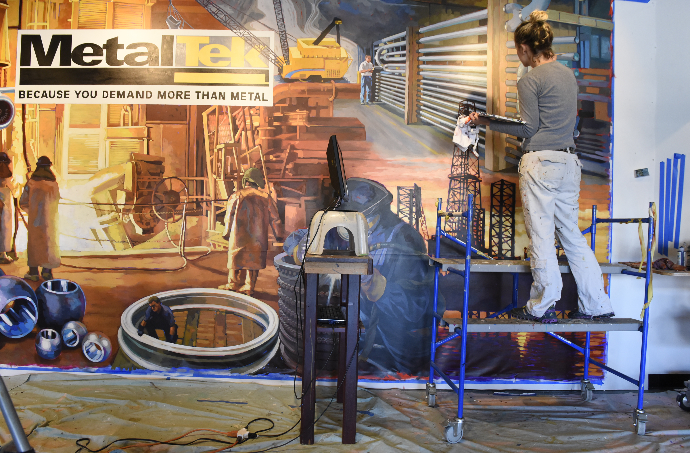 Ali Kay works on a mural in the lobby of the Chattanooga WorkSpace building on Thursday, Nov. 19, 2015, in Chattanooga, Tenn. This mural, eight feet tall and 21 feet wide, is one of eight of her murals that will be displayed in offices of MetalTek around the country.