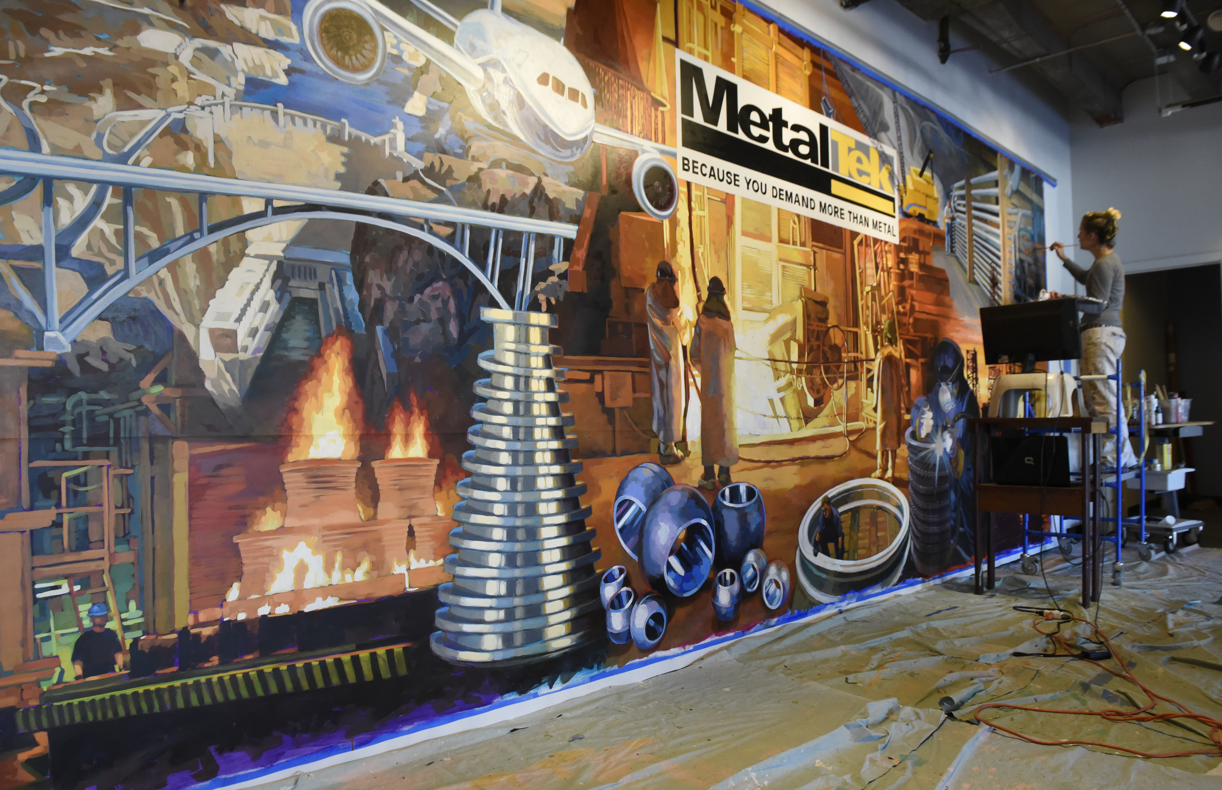 Ali Kay works on a mural in the lobby of the Chattanooga WorkSpace building on Thursday, Nov. 19, 2015, in Chattanooga, Tenn. This mural, eight feet tall and 21 feet wide, is one of eight of her murals that will be displayed in offices of MetalTek around the country.