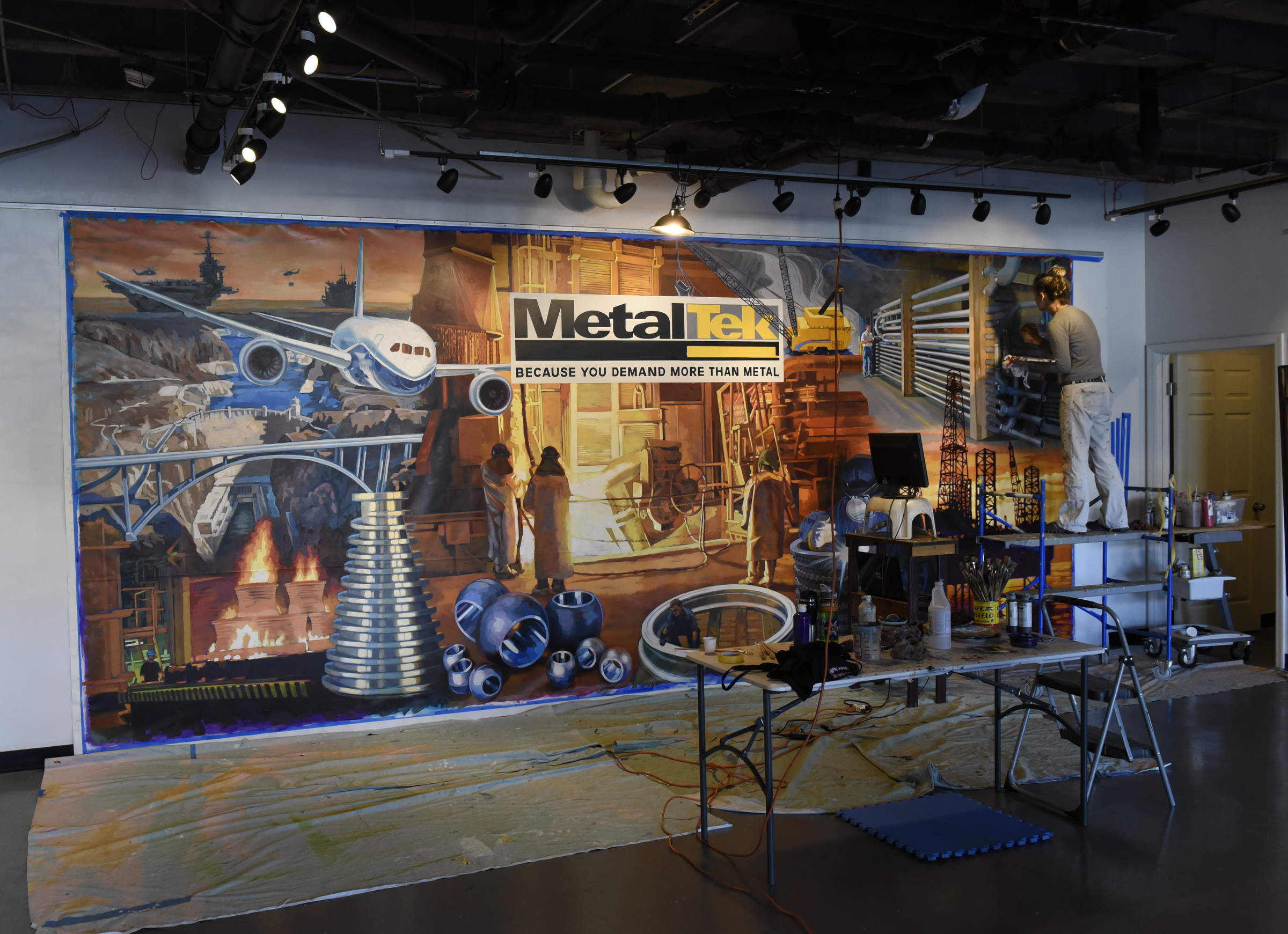 Ali Kay works on a mural in the lobby of the Chattanooga WorkSpace building on Thursday, Nov. 19, 2015, in Chattanooga, Tenn. This mural, eight feet tall and 21 feet wide, is one of eight of her murals that will be displayed in offices of MetalTek around the country.