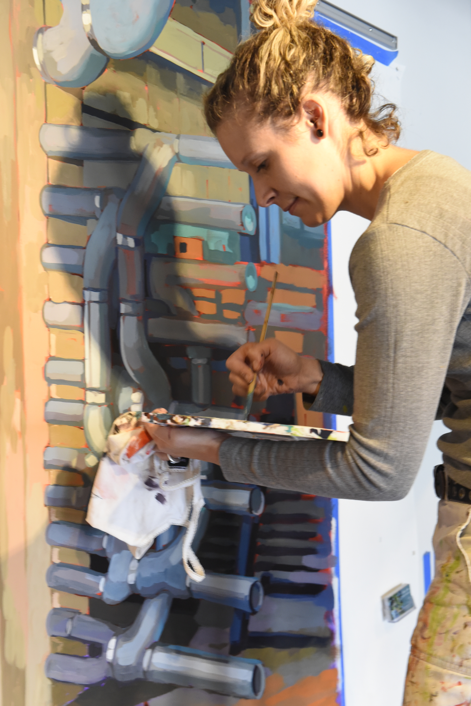 Ali Kay works on a mural in the lobby of the Chattanooga WorkSpace building on Thursday, Nov. 19, 2015, in Chattanooga, Tenn. This mural, eight feet tall and 21 feet wide, is one of eight of her murals that will be displayed in offices of MetalTek around the country.