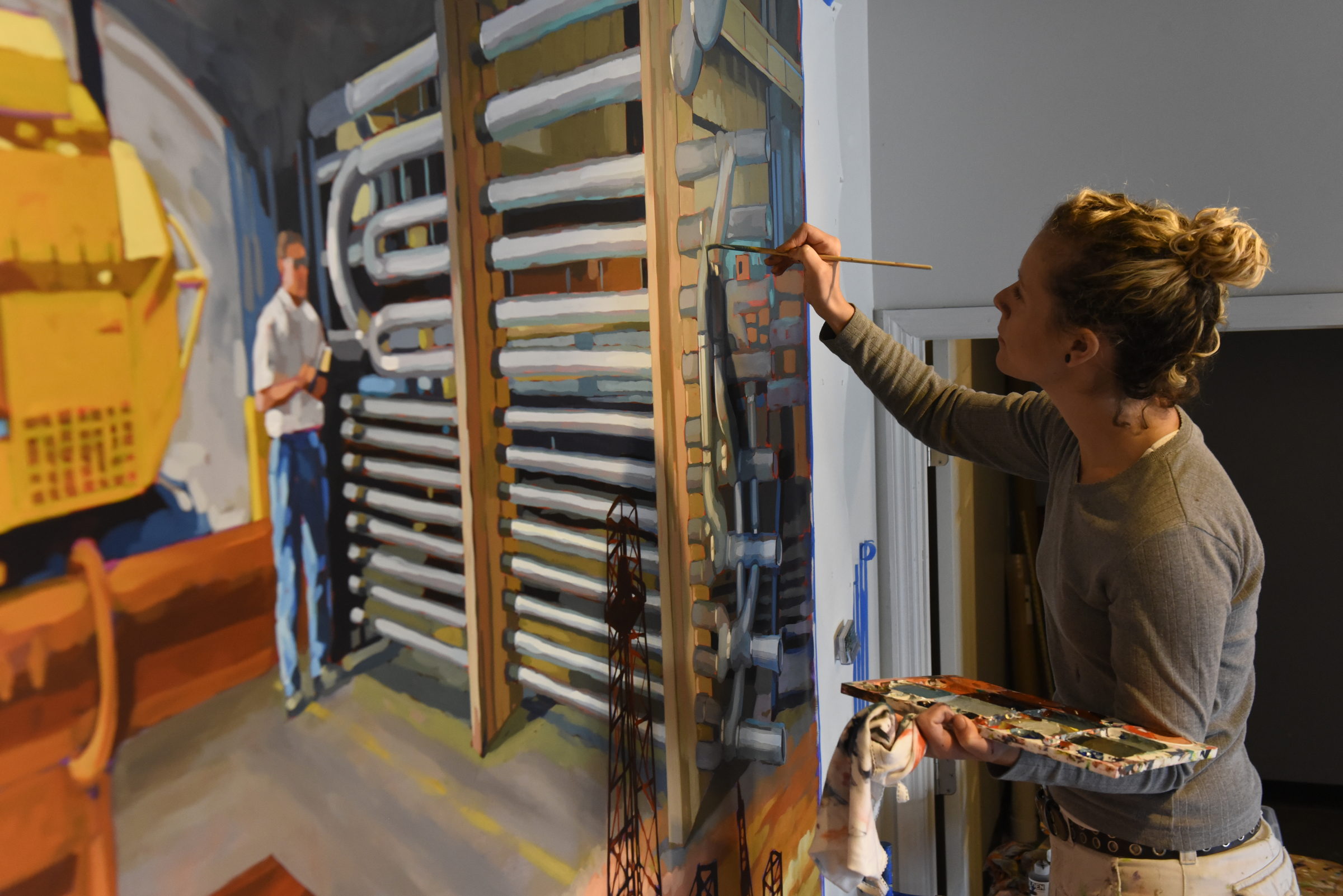 Ali Kay works on a mural in the lobby of the Chattanooga WorkSpace building on Thursday, Nov. 19, 2015, in Chattanooga, Tenn. This mural, eight feet tall and 21 feet wide, is one of eight of her murals that will be displayed in offices of MetalTek around the country.