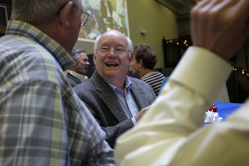 Don Smith, left, gives Pete Cooper a gift at at a retirement party for Cooper at the Community Foundation of Greater Chattanooga on Thursday, Dec. 10, 2015, in Chattanooga, Tenn.