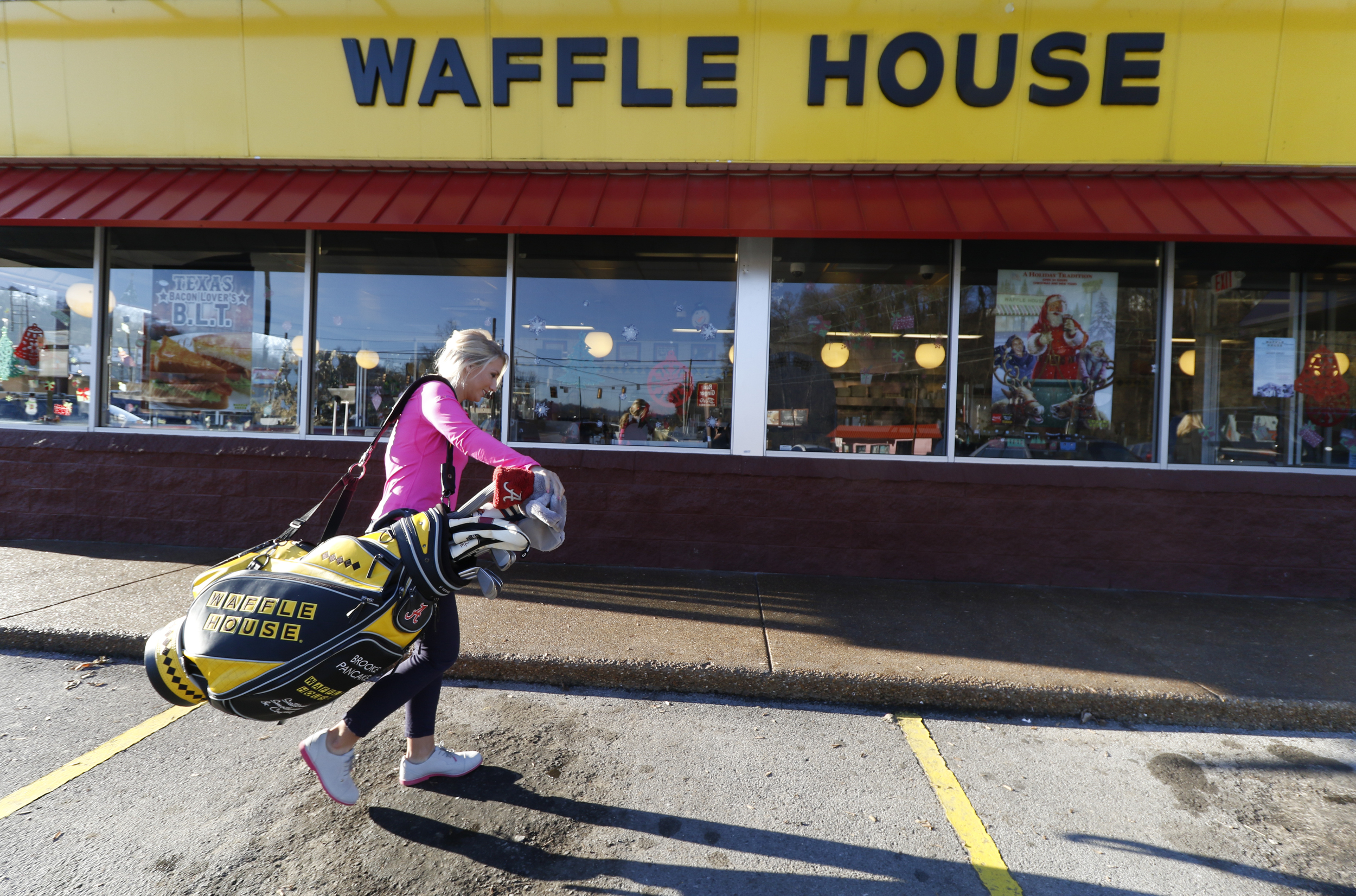 Staff Photo by Dan Henry / The Chattanooga Times Free Press- 12/16/15. Baylor School golfer Brooke Pancake, who now plays on the professional women's golf tour and has signed an endorsement deal with Waffle House, carries her bag inside of the Red Bank restaurant to partake in a promotional photo shoot on Wednesday, December 16, 2015.
