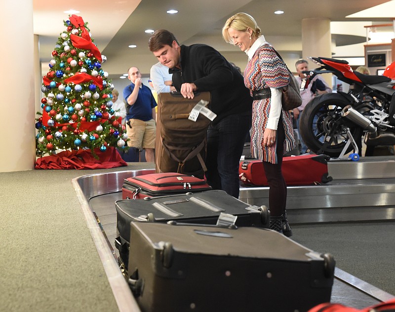 Drew Altman, right, waits with her son, Hilsman Knight as he gets his luggage upon arrival at Chattanooga Metropolitan Airport.