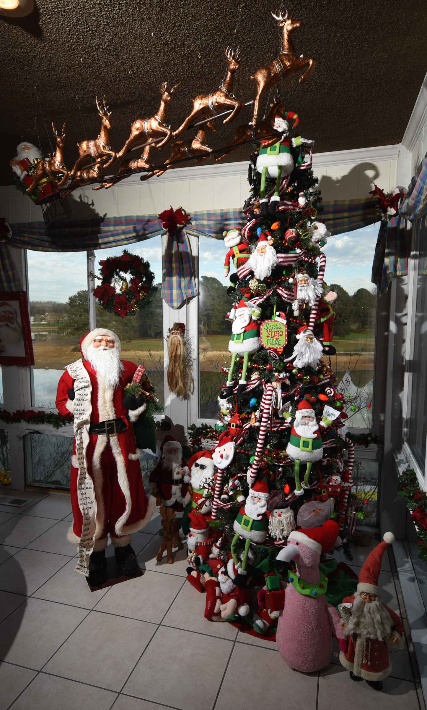 The variety of Santas on and around the sunroom's tree includes a 5-f00t Santa, fabric ornaments, cool Santa in shades, Santa flamingo, Santa gnome and Santa in his sleigh.