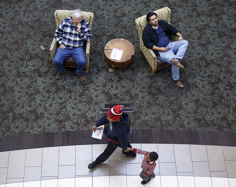 Shoppers relax in armchairs as others walk past at Hamilton Place Mall on Friday, Dec. 18, 2015, in Chattanooga, Tenn. This weekend is one of the busiest shopping weekends of the year.