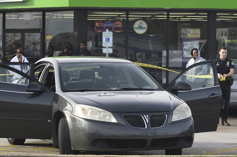 Chattanooga Police Department officers investigate a shooting that occurred near the intersection of Third Street and Holtzclaw Avenue on Sunday, Dec. 20, 2015, in Chattanooga, Tenn. One victim was transported by ambulance after the driver pulled into the parking lot of the Mapco in the aftermath of a shooting that shattered the passenger window and left a bullet hole in the front windshield. 