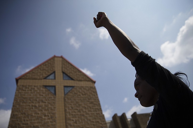 
              FILE - In this Tuesday, July 28, 2015 file photo, mourner JeRee Wilson holds her fist in the air outside funeral services for Samuel Dubose at the Church of the Living God in the Avondale neighborhood of Cincinnati. Dubose was fatally shot by a University of Cincinnati police officer who stopped him for a missing license plate. Volatile, racially sensitive questions of whether to charge police officers for fatal on-duty shootings, and whether jurors will convict an officer in such a case, hang over two of Ohio's largest cities. (AP Photo/John Minchillo, File)
            