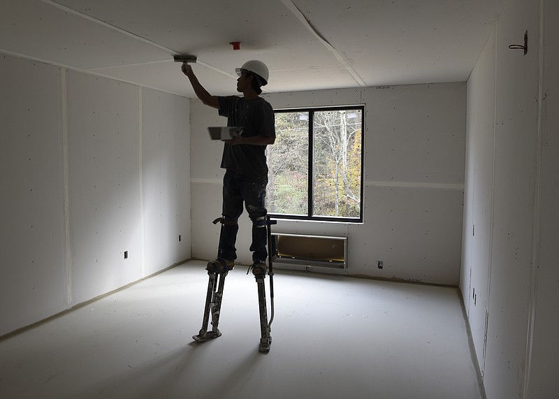 Richardo Gomes finishes drywall work in a hotel construction project.