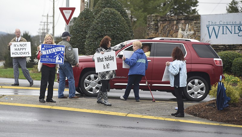 Charlie Wysong, Jan Frazier, Bill Reesor, Patty Currey, Mary Lynn Jones and Louise Reesor, from left, hold signs on Wednesday, Dec. 23, 2015, at the entrance to the Windstone subdivision on Ooltewah-Ringgold Road, just south of the Tennessee state line. They are upset that a sign in the subdivision wishes residents "happy holidays" instead of "merry Christmas."