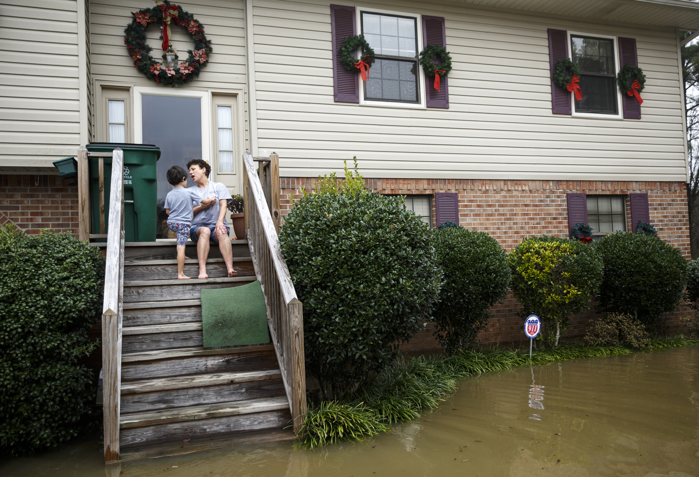 Freida Wheeler sits with her grandson Cannon Smith on the porch of her home as floodwaters rise to the stairs after heavy rains brought flooding to the region Saturday, Dec. 26, 2015, in East Ridge, Tenn. Rain is expected to continue into the next week.