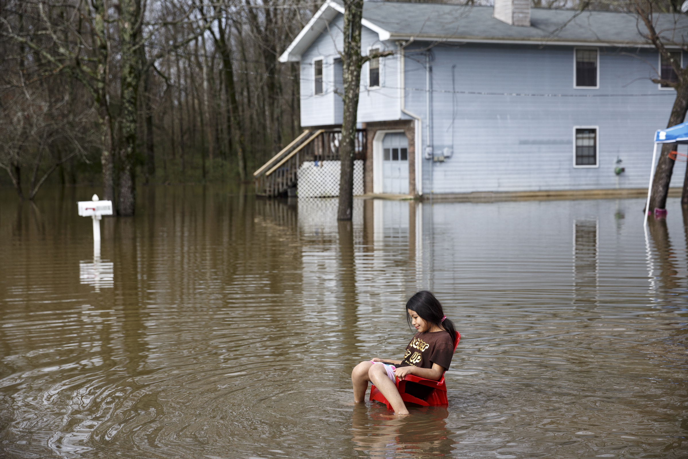 A girl sits in floodwaters on Wentworth Avenue after heavy rains brought flooding to the region Saturday, Dec. 26, 2015, in East Ridge, Tenn. Rain is expected to continue into the next week.