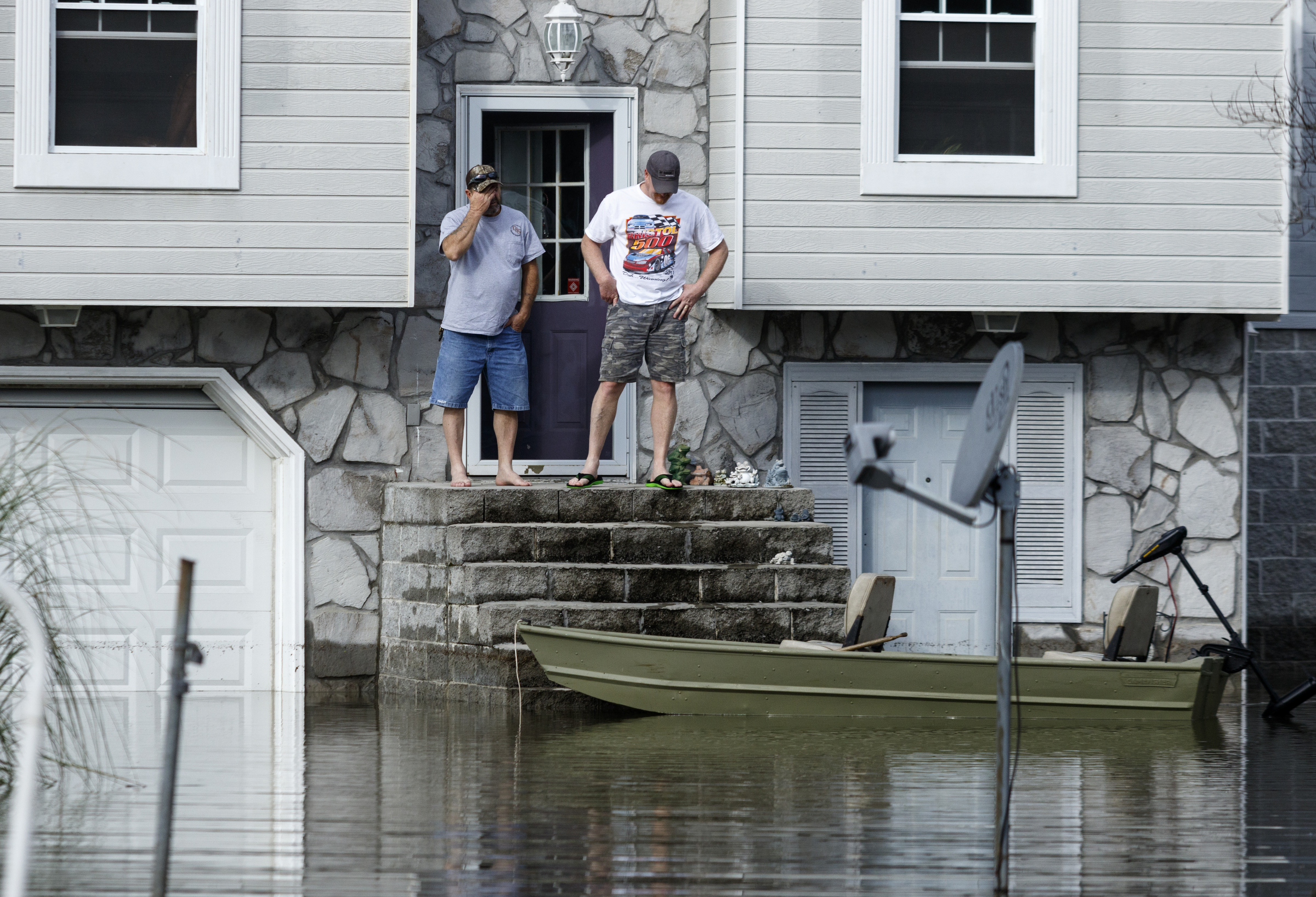 Men look out at flooding from a home on Welworth Avenue after Christmas day rainfall brought South Chickamauga Creek to a flood stage of about 26.5 feet on Sunday, Dec. 27, 2015, in East Ridge, Tenn. Major flood stage classification for the creek is 27 feet.