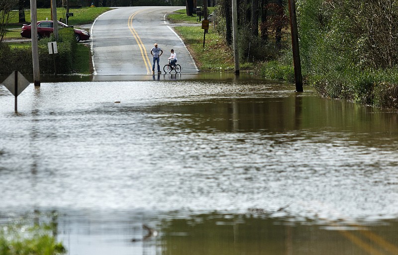 People look at floodwaters blocking South Mack Smith Road after Christmas day rainfall brought South Chickamauga Creek to a flood stage of about 26.5 feet on Sunday, Dec. 27, 2015, in Fort Oglethorpe, Ga. Major flood stage classification for the creek is 27 feet.