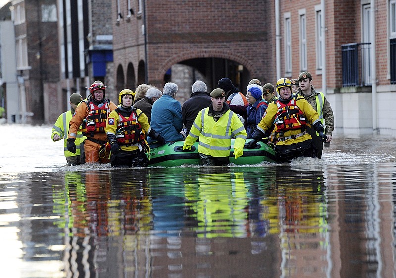 
              Members of the army and rescue teams help evacuate people from flooded properties after they became trapped by rising floodwater when the River Ouse bursts its banks in York city center Sunday, Dec. 27, 2015. Homes were evacuated, cars were submerged and boats were brought in to help bring people to safety Saturday as parts of England, Scotland and Wales faced severe flooding caused by repeated heavy rains. (John Giles/PA via AP) UNITED KINGDOM OUT, NO SALES, NO ARCHIVE
            
