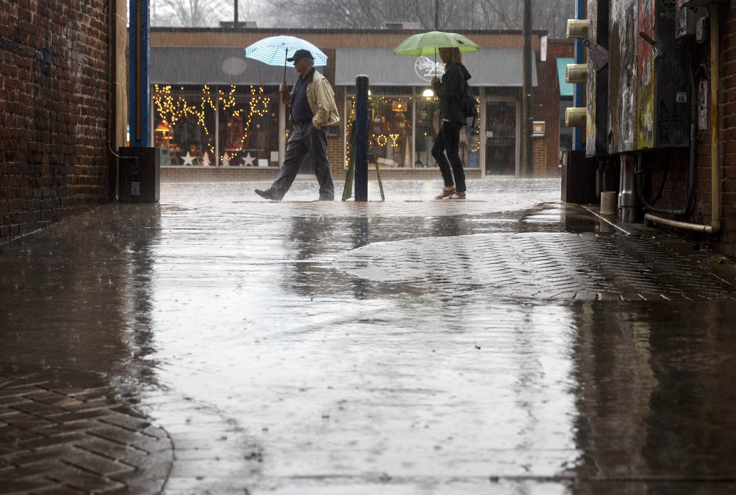 Pedestrians walk along Frazier Avenue during afternoon rainfall after additional storms swept through the region Monday, Dec. 28, 2015, in Chattanooga, Tenn. The region recorded record-high temperatures over the past week amid heavy rainfall.