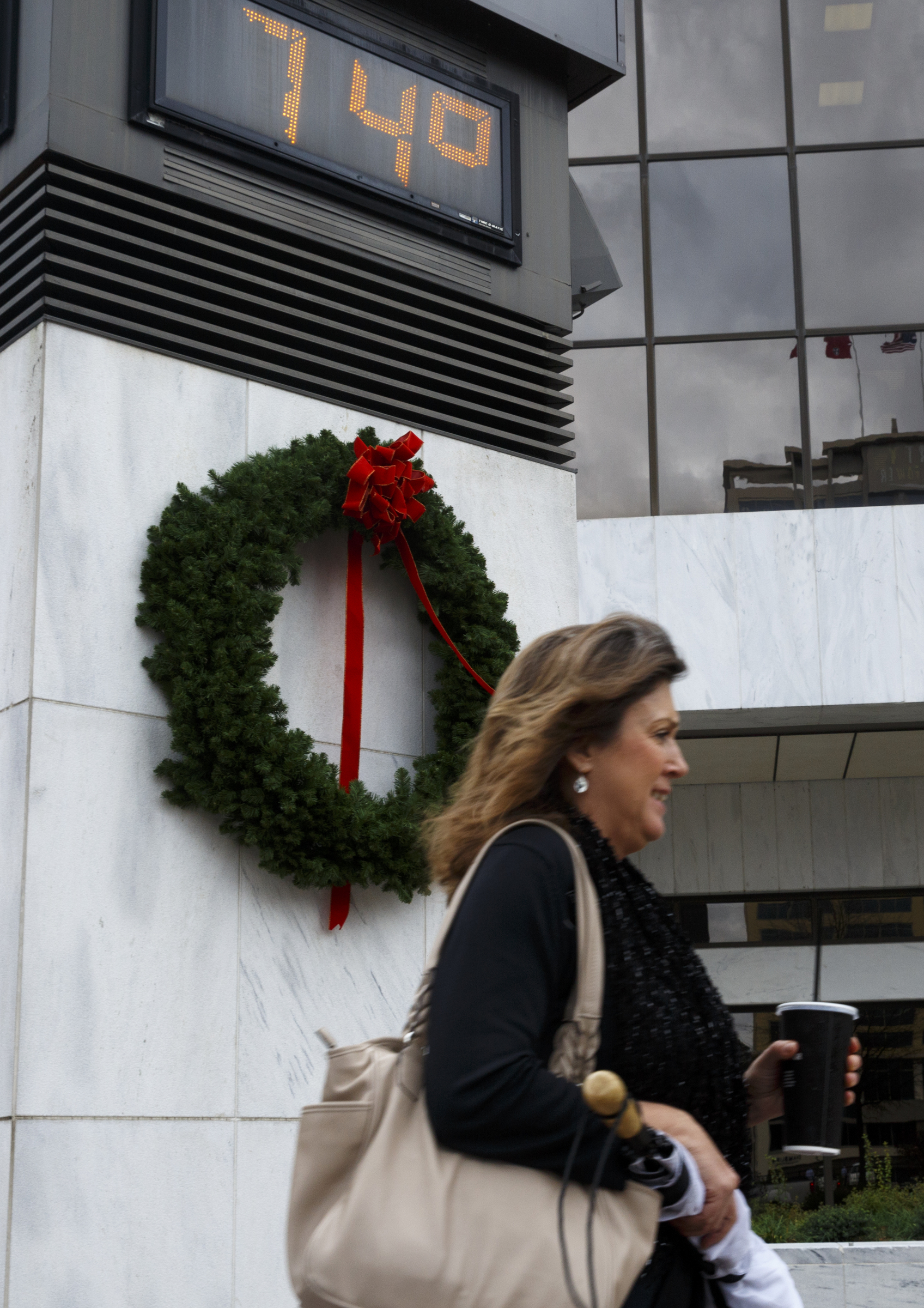 Linda Green walks past a temperature readout on a sign downtown Monday, Dec. 28, 2015, in Chattanooga, Tenn. The region has experienced record-high temperatures over the past week.