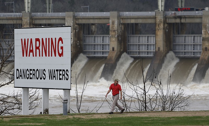 Josh Dove makes his way along the riverwalk at Chickamauga Dam as a large flow of water pours through the spillway on Monday.