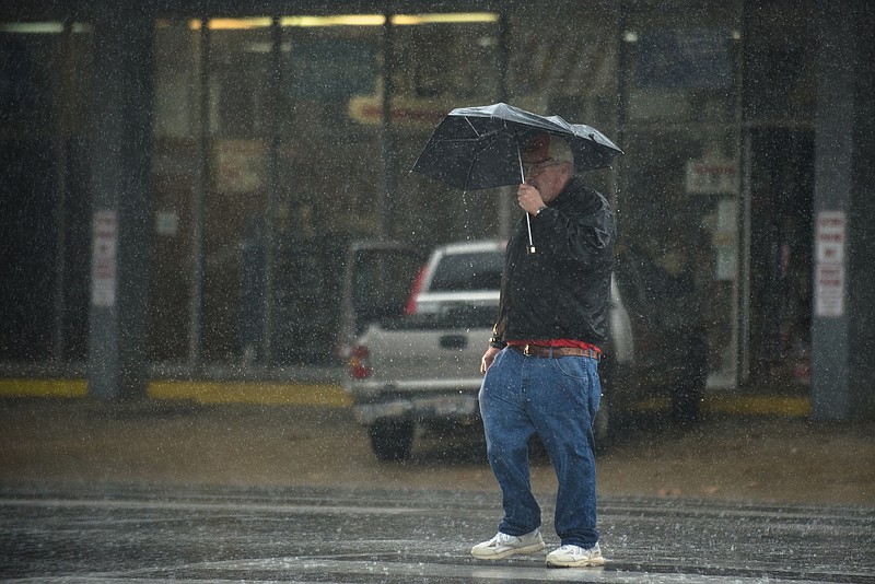 A pedestrian walks through the rain in downtown Montgomery, Ala., on Monday, Dec. 28, 2015.