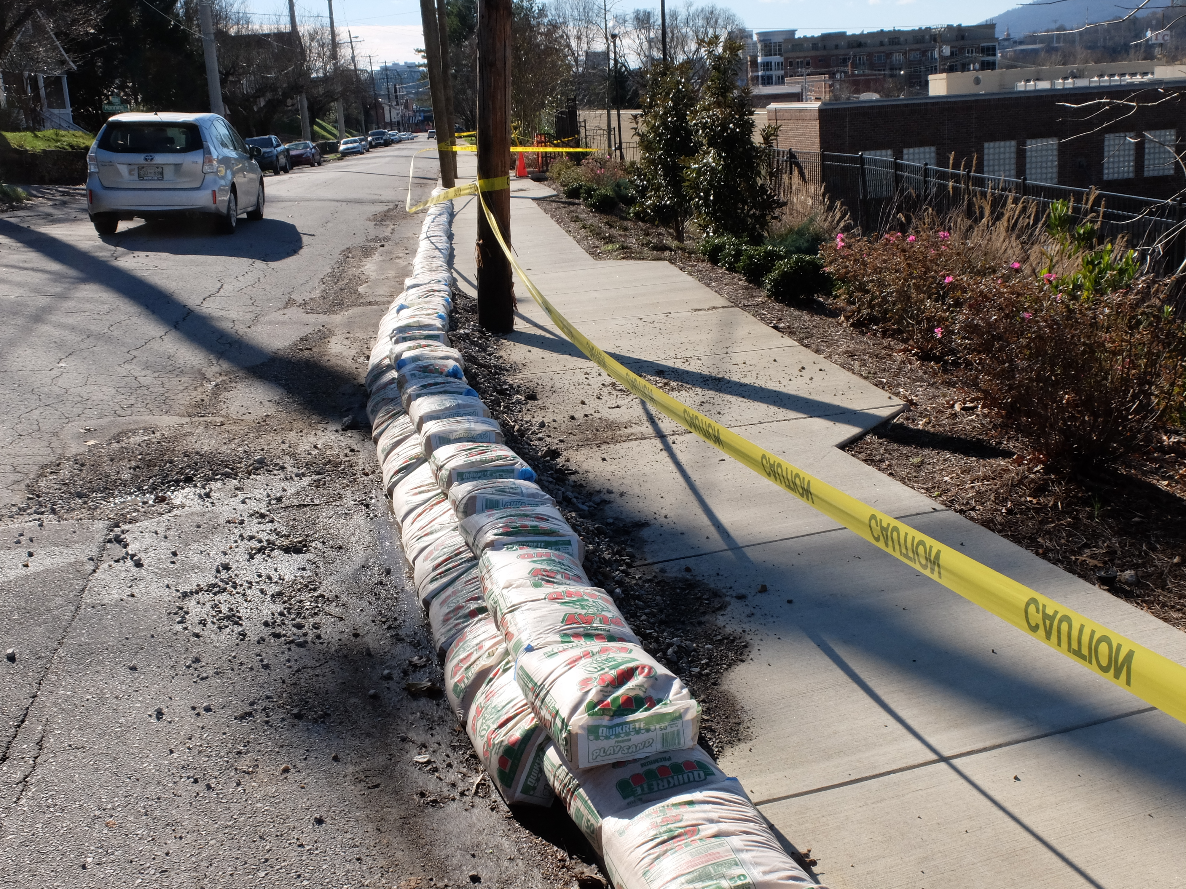 Yellow caution tape blocks the sidewalk and sand bags have been placed in the roadway along Woodland and Hamilton Avenues. The retaining wall on the east side of the Publix parking lot is suspected of moving as a result of recent heavy rains.