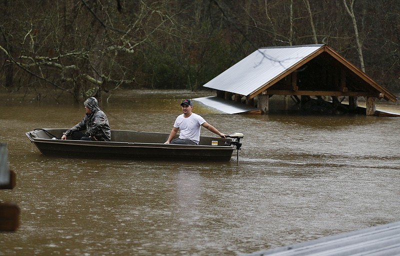 Two men in a boat explore a flooded business near along Copper Creek Monday, Dec. 28, 2015, in Calhoun, Ga. Heavy rain caused flooding in parts of the state.