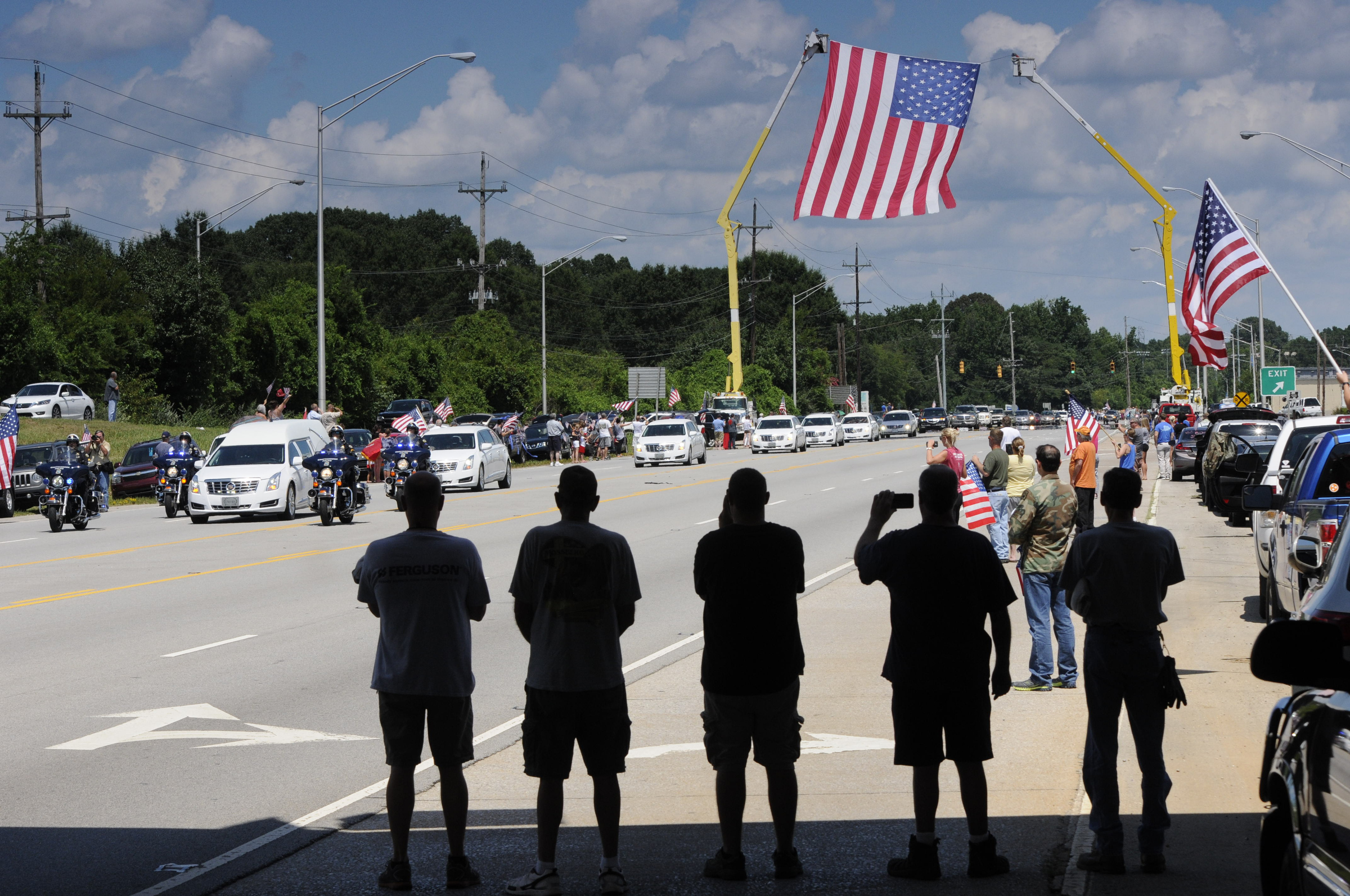 The hearse, middle left, carrying Staff Sgt. David Wyatt passes on Amnicola Highway at DuPont Parkway, where the Electric Power Board erected an American flag over the road with two bucket trucks.