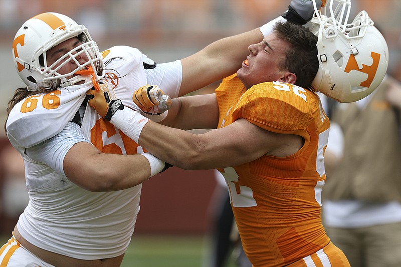 The University of Tennessee's Andrew Butcher (52) has his helmet ripped off by Jack Jones (66) during the Dish Orange & White Game in Knoxville on April 25, 2015.