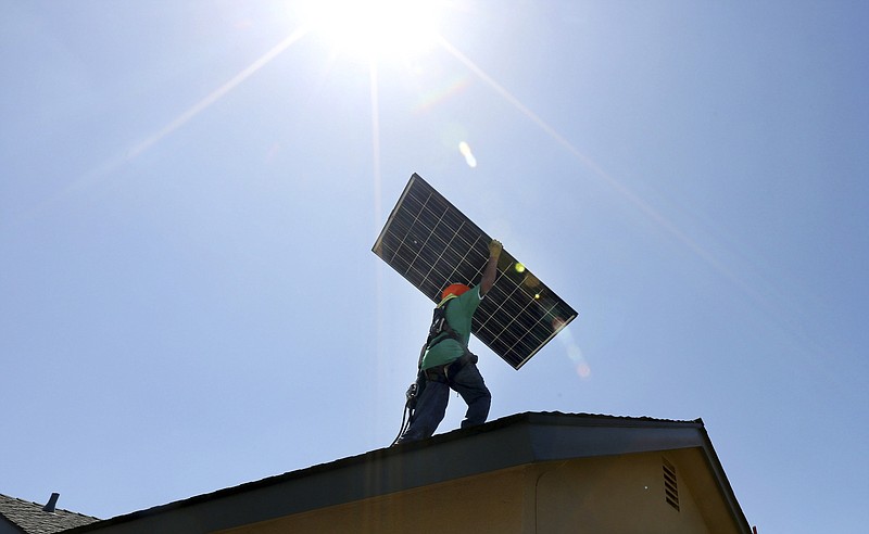 Workers install solar panels on a home. (J. Emilio Flores/The New York Times)