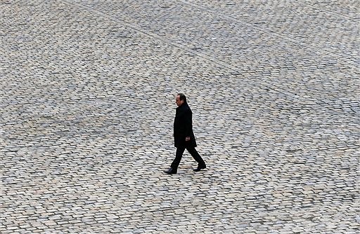 French President Francois Hollande walks in the courtyard of the Invalides national monument during a ceremony in Paris, Friday, Nov. 27, 2015. Intoning the names of 130 dead, a subdued France paid homage Friday to those killed two weeks ago in the attacks that gripped Paris in fear and mourning. (AP Photo/Francois Mori)