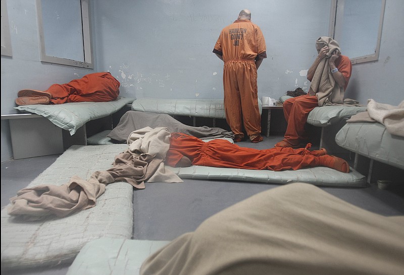 Men sit along the wall and lie on the floor as they wait to be assigned a cell upstairs at the Hamilton County Jail. Jail officials are seeking ways to alleviate overcrowding, which has been a problem for several years.