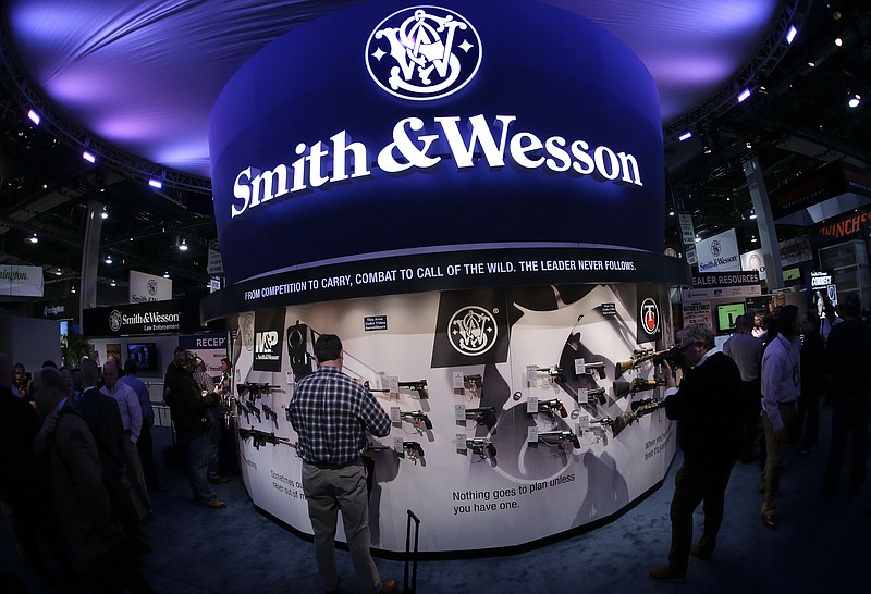 FILE - In this Tuesday, Jan. 14, 2014, file photo, trade show attendees examine handguns and rifles in the Smith & Wesson display boot at the Shooting Hunting and Outdoor Tradeshow, in Las Vegas. (AP Photo/Julie Jacobson, File)
            