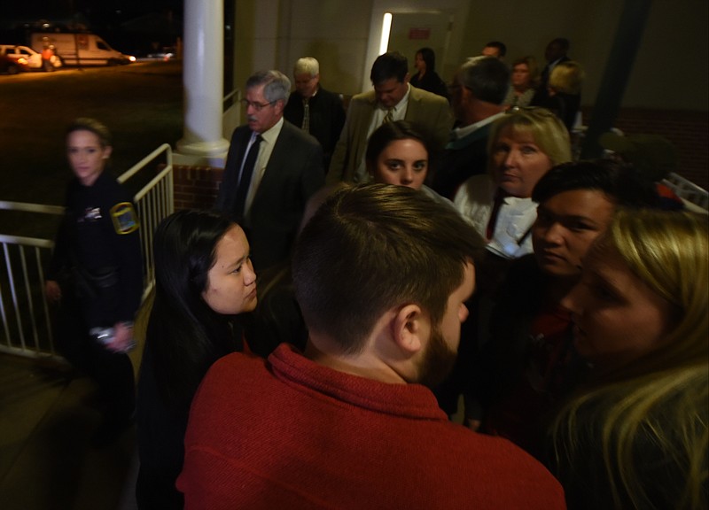 A Hamilton County Sheriff's Deputy, left, escorts School Board Superintendent Rick Smith out of the building past a group of Ooltewah students Wednesday night. Students, clockwise from left include Bria Miller, Lexie Godsey, parent Tammy Matthews, Bradley Miller, Hanna Matthews and Cade Starling.