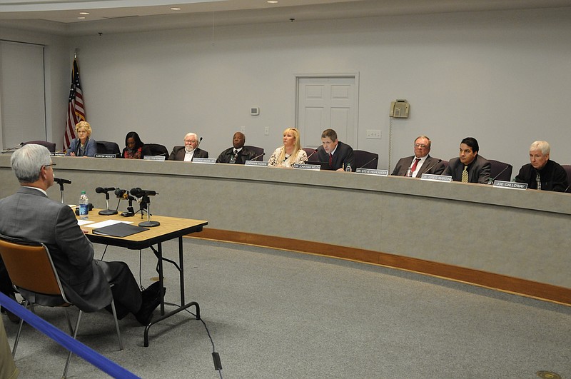 The Hamilton County School Board Chairman Jonathan Welch, center, reads a prepared statement to an overflow crowd Wednesday night as School Superintendent Rick Smith, left, listens.