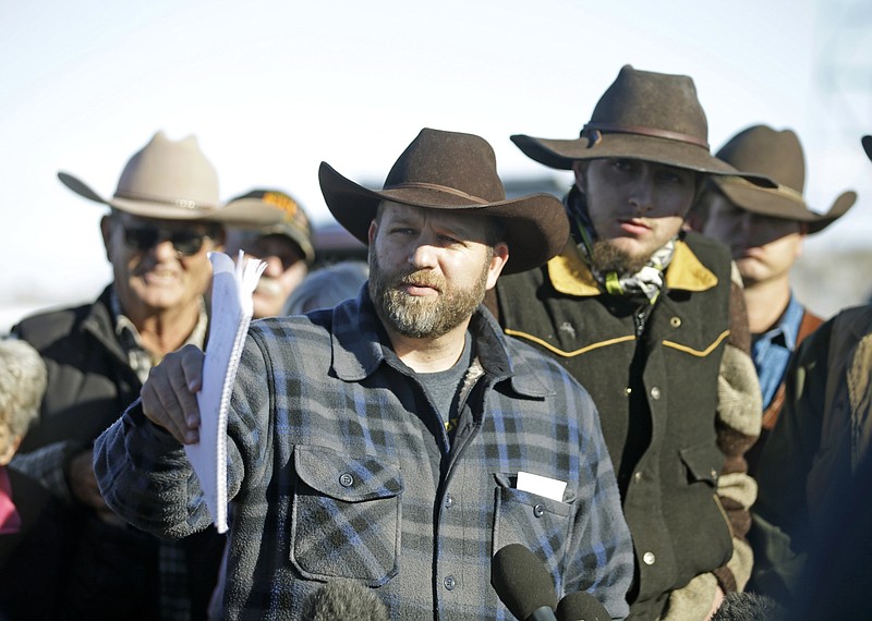 Ammon Bundy, center, speaks with a reporter at a news conference at Malheur National Wildlife Refuge on Friday near Burns, Ore. Bundy, the leader of an armed group occupying the national wildlife refuge to protest federal land management policies, said Friday he and his followers are not ready to leave even though the sheriff and many locals say the group has overstayed their welcome. (AP Photo/Rick Bowmer)