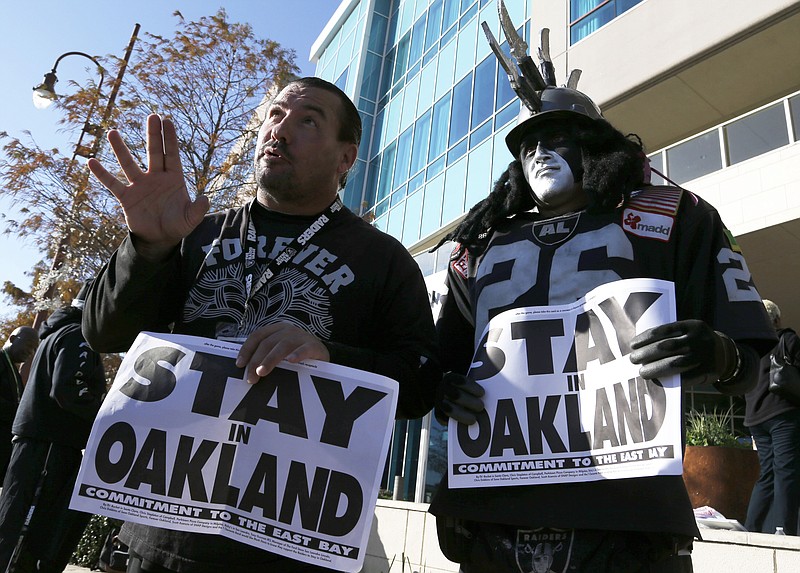 Oakland Raiders fans Griz Jones, left, and Ray Perez make their case for keeping the NFL football team in Oakland outside the hotel where NFL owners are meeting Tuesday, Jan. 12, 2016, in Houston to discuss possible relocation to Los Angeles.