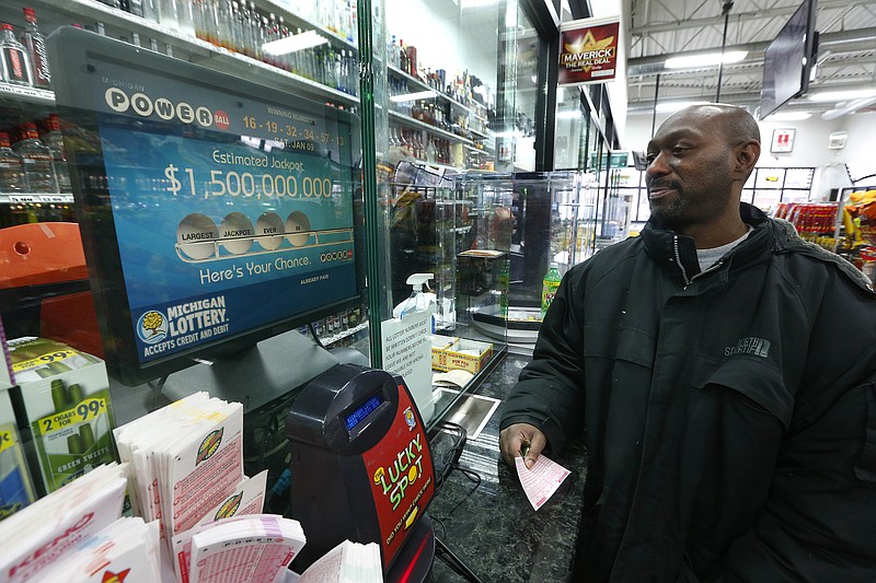 
              Tim Jackson buys Powerball tickets at Coach Liquor in Detroit, Wednesday, Jan. 13, 2016. A lottery official says the estimated Powerball jackpot will be over a billion. (AP Photo/Paul Sancya)
            